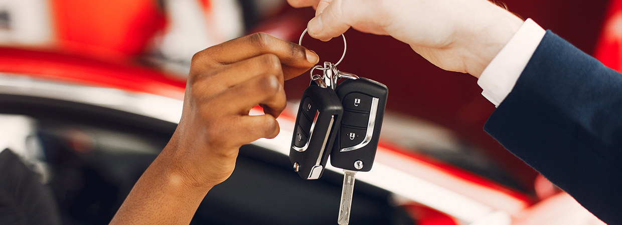 Mãos passando chave do carro entre si representando a transferência de propriedade de um veículo